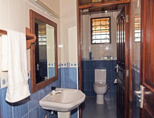 een blauwe en witte badkamer met een wastafel en een toilet bij Galu Gardens Apartments Diani Beach in Diani Beach