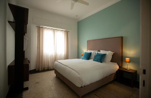 ein Schlafzimmer mit einem Bett mit blauen Kissen und einem Fenster in der Unterkunft Suite Balima XI in Rabat