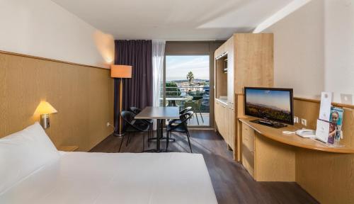 アンティーブにあるThalazur Antibes - Résidence & Spaのベッド、デスク、コンピュータが備わるホテルルームです。