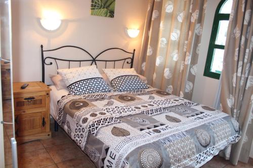 een slaapkamer met een bed met een zwart-wit dekbed bij Bungalow Duna Flor Verde in Maspalomas