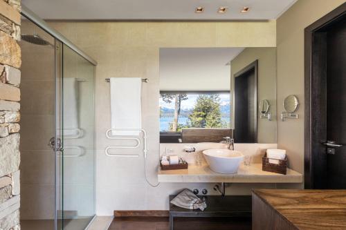 a bathroom with a sink and a glass shower at Calfuco Wine Hotel & Spa in Villa La Angostura