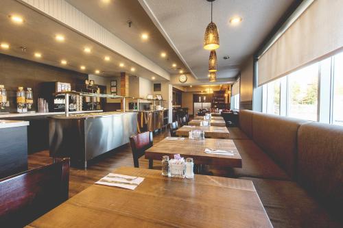 una sala da pranzo con tavoli in legno e un bar di Hotel Continental Centre-Ville a Val-d'Or