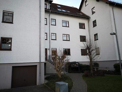 ein großes weißes Gebäude mit einer Garage davor in der Unterkunft Ferienwohnung Schreckenbach in Sankt Egidien