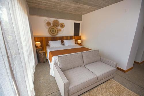 a small bedroom with a bed and a couch at Aldeia do Mar Sensorial Hotel in Itacaré