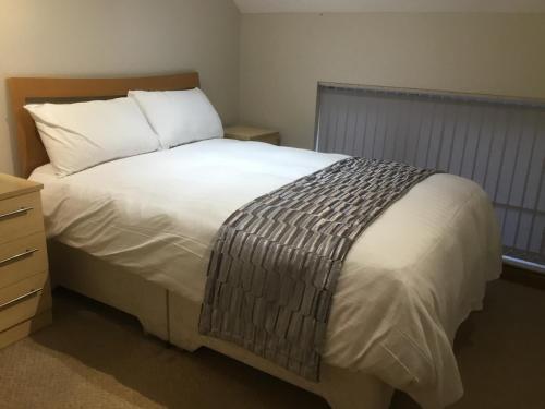 een slaapkamer met een wit bed en een houten hoofdeinde bij The Loco in Doncaster