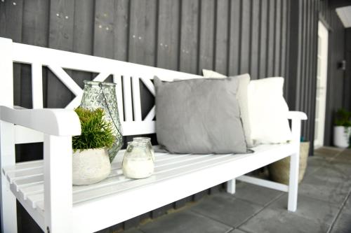 a white bench with pillows and plants on a porch at Hotel Skovpavillonen in Kerteminde
