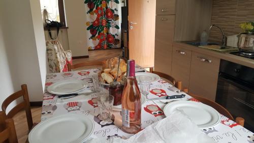 a table with white plates and a bottle of wine at Casa Ramus Valle Camonica a 30 km dal Passo Tonale in Edolo