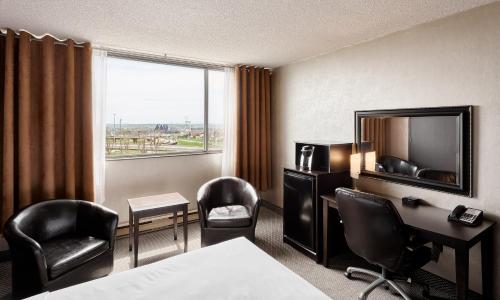 a hotel room with a bed and a desk and chairs at Travelodge by Wyndham Quebec City Hotel & Convention Centre in Quebec City