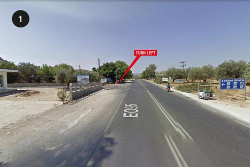 a road with a sign that says turn left at Villa Stavros in Archangelos