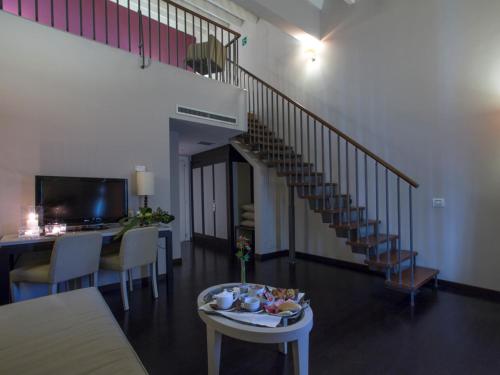 a living room with a staircase and a table with food on it at Grand Hotel Villa Itria Congress & Spa in Viagrande