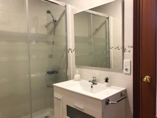 een badkamer met een wastafel en een douche met een spiegel bij APARTAMENTOs IGLESIA DE SANTIAGO in Jerez de la Frontera