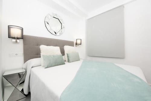 a white bedroom with a large bed with a green blanket at Benigno Premium Center in Málaga