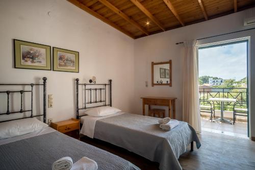 a bedroom with two beds and a large window at Barax Apartments in Agios Georgios