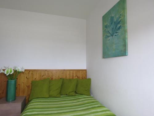 a bed with green sheets in a room with a painting at Casa da Praia in Praia da Vieira