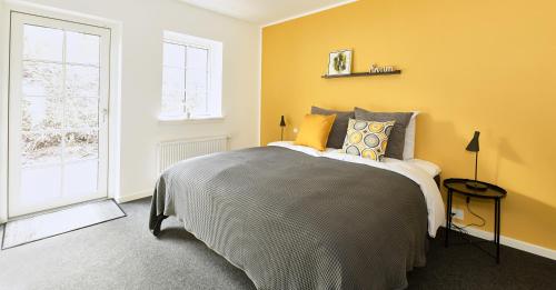 a bedroom with a bed with yellow walls and a window at Hotel Skovpavillonen in Kerteminde
