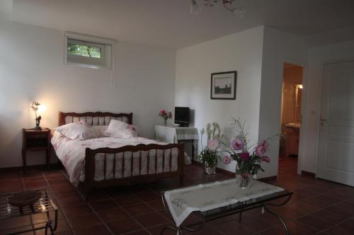 Les Vallées du Guyoult في دول-دي-بروتاني: غرفة نوم بسرير وطاولة مع ورد