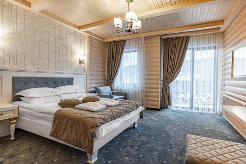 1 dormitorio con cama grande y ventana grande en MARION SPA - Breakfast included in the price Spa Swimming pool Sauna Hammam Jacuzzi Salt room Children's room Restaurant Parking 400 m to Bukovel Lift 1 Mountain view en Bukovel