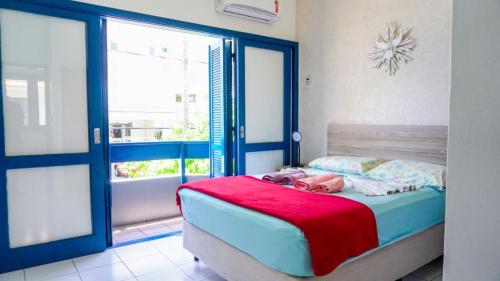 um quarto com uma cama com um cobertor vermelho em Casa VERDE - A 70 Metros da Areia da Praia dos Ingleses - 6 Pessoas em Florianópolis