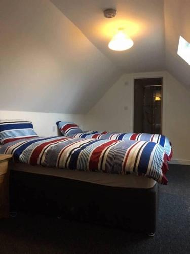 a bed with a striped blanket on it in a room at Orchard Cottage in Canterbury