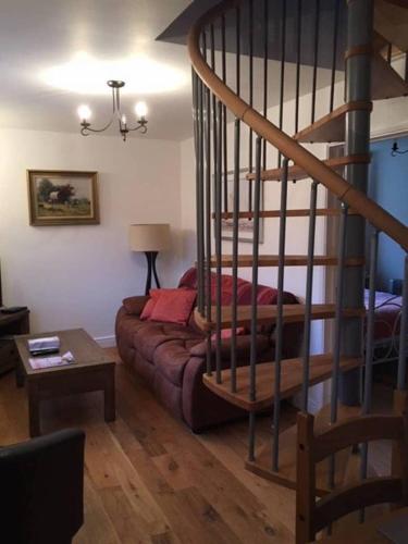 a living room with a couch and a spiral staircase at Orchard Cottage in Canterbury