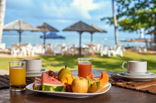 a plate of fruit and juice on a table near the beach at Aldeia do Mar Sensorial Hotel in Itacaré
