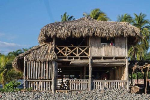 a hut with a straw roof on a beach at Pelicano Surf Camp in La Libertad