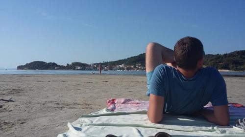 a man sitting on a towel on the beach at Vila Marija in Rab