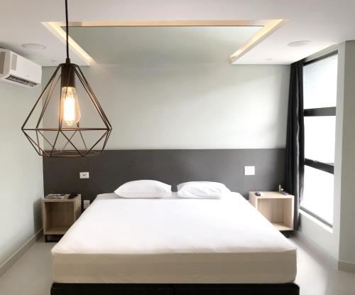 a bedroom with a large white bed and a chandelier at Drops Motel Brasília in Brasilia