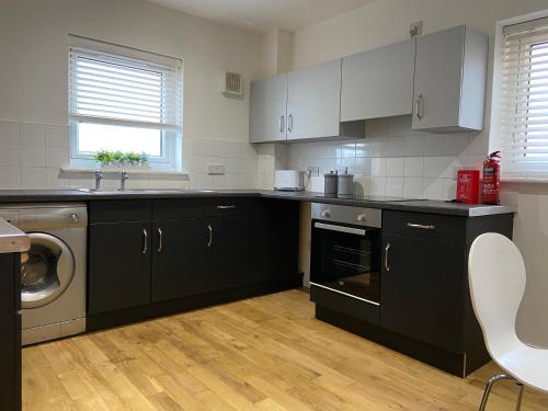 a kitchen with black cabinets and a sink and a dishwasher at Gateway Apartment in Inverness