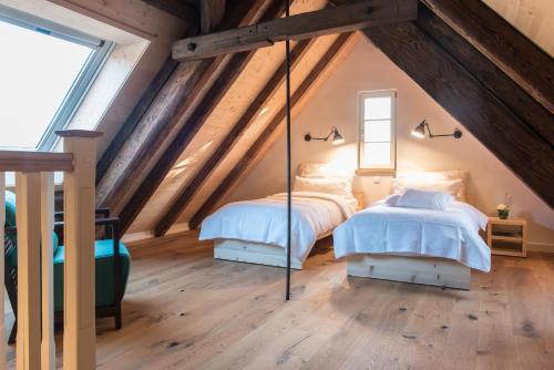 two beds in a attic bedroom with wooden ceilings at Palais Wunderlich in Lahr