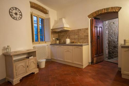 een keuken met witte kasten en een klok aan de muur bij La Terrazza sul Borgo - Montefioralle Apartment in Greve in Chianti