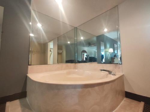 baño con bañera y espejo grande en Travelodge by Wyndham Alachua, en Alachua