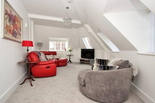 sala de estar con silla roja y sofá en CC - Central Location Top Floor 2 Bed Deluxe Modern Apartment en Stratford-upon-Avon