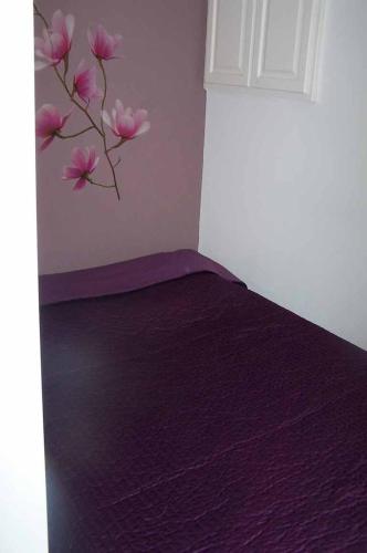 - une chambre avec un lit violet et une branche ornée de fleurs roses dans l'établissement LA CALANQUE 263, aux Issambres