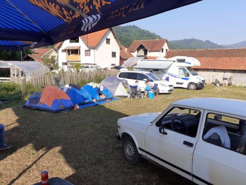 un groupe de tentes et une voiture garée dans une cour dans l'établissement Dragacevska avlija - Camp, à Guča