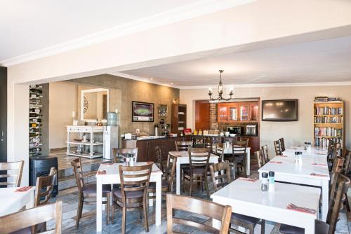 Un comedor con mesas y sillas blancas. en Ruth Avenue Guest House, en Edenvale