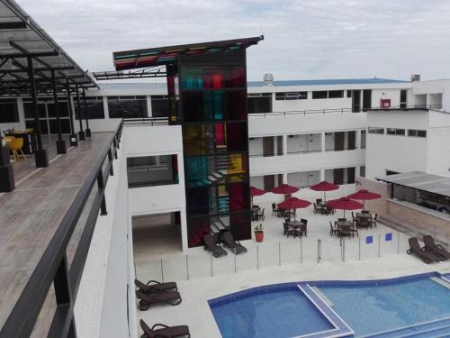 un edificio con piscina, mesas y sombrillas en Hotel Karmel, en Melgar