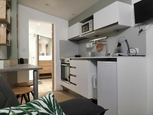 a kitchen with white cabinets and a table in a room at Le cabanon in Méneslies