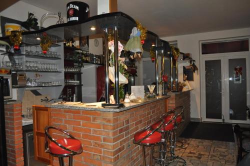 a bar with red stools in front of a brick counter at Ubytovanie Škulec in Stará Turá