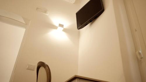 a bathroom with a toilet with a television on the wall at La Maison in Taranto