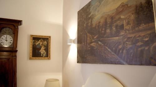 a clock and a painting on a wall next to a clock at La Maison in Taranto