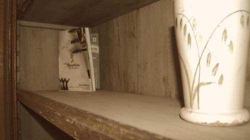 a shelf with a book and a vase on it at La Maison in Taranto