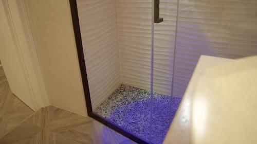 a shower with a glass door with purple gravel at La Maison in Taranto