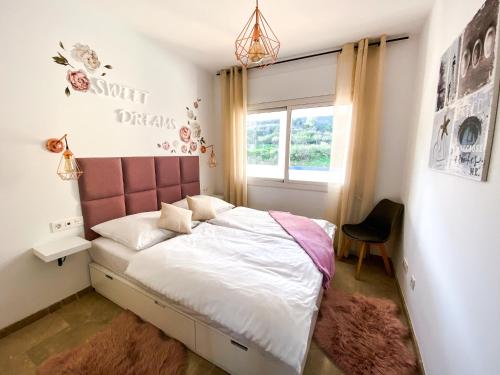 a bedroom with a bed with a pink headboard and a window at Beautiful New Apartment with Sea View in Castillo de Sabinillas