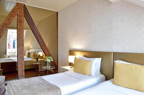 um quarto de hotel com duas camas e um espelho em My Story Hotel Ouro em Lisboa