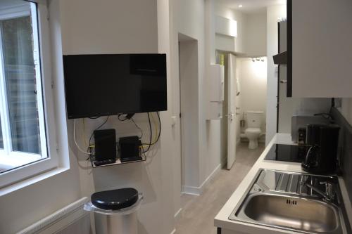 Il comprend une cuisine avec un évier et une télévision murale. dans l'établissement Petit T2 hypercentre avec terrasse privée - 006, à Rouen