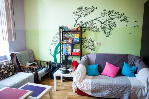 a living room with a couch and a tree mural on the wall at Hostel Centrum Sabot in Krakow