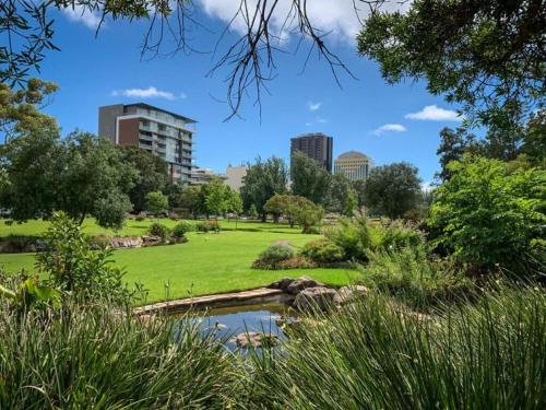 a park with a pond and buildings in the background at Adelaide Pulteney Motel in Adelaide