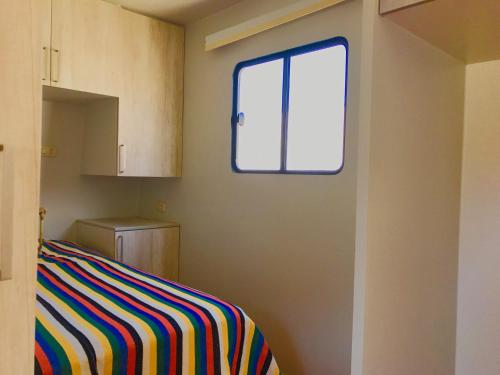 Dormitorio con ventana y cama a rayas en Patitos en Huarmey