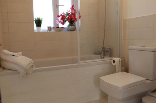uma casa de banho com um WC, uma banheira e uma janela. em Cosy & Lovely Guesthouse with Free Parking & Close to Station em Slades Green